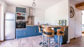 Una cocina moderna con gabinetes azules, un refrigerador de acero inoxidable, un microondas, un horno y una isla de madera con taburetes de bar.