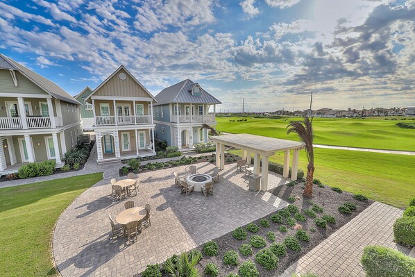 A large house with a patio area, a pool, and a view of a golf course.