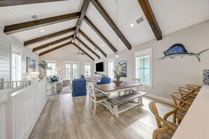 A spacious dining area with a wooden table and benches, a white railing along one side, and a large fish decoration on the wall.