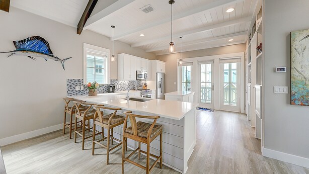 A spacious kitchen with a large island, wooden bar stools, and modern appliances. - Beautiful golf course view home at Palmilla Beach Resort with resort pool (Port Aransas)