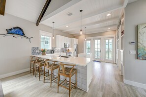 A spacious kitchen with a large island, wooden bar stools, and modern appliances.