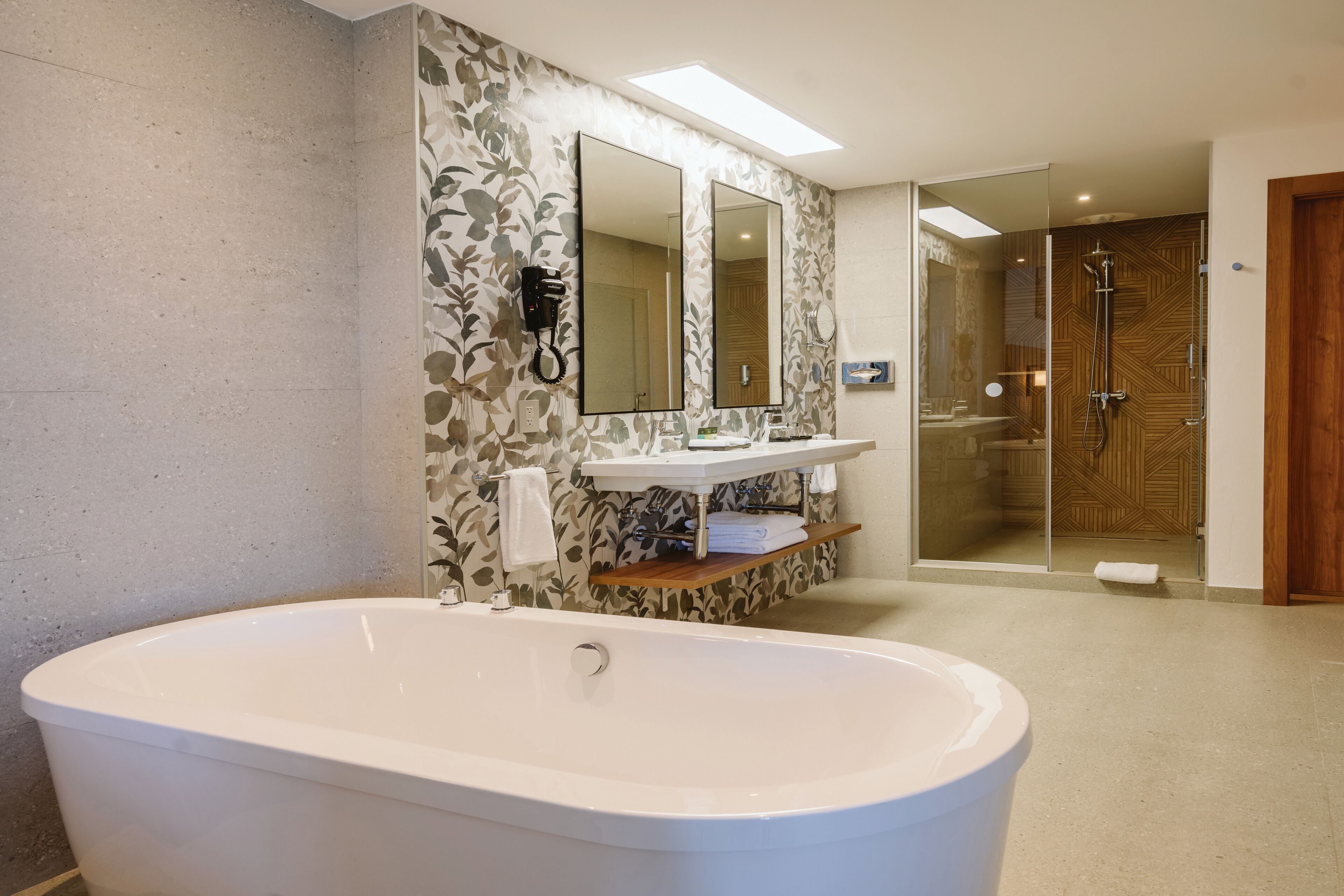 Un baño moderno con una bañera independiente, un espejo grande, un tocador con lavabo y una zona de ducha.