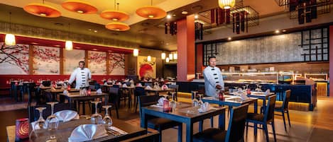 Un restaurante con varias mesas, personal de servicio y una zona de bufé.