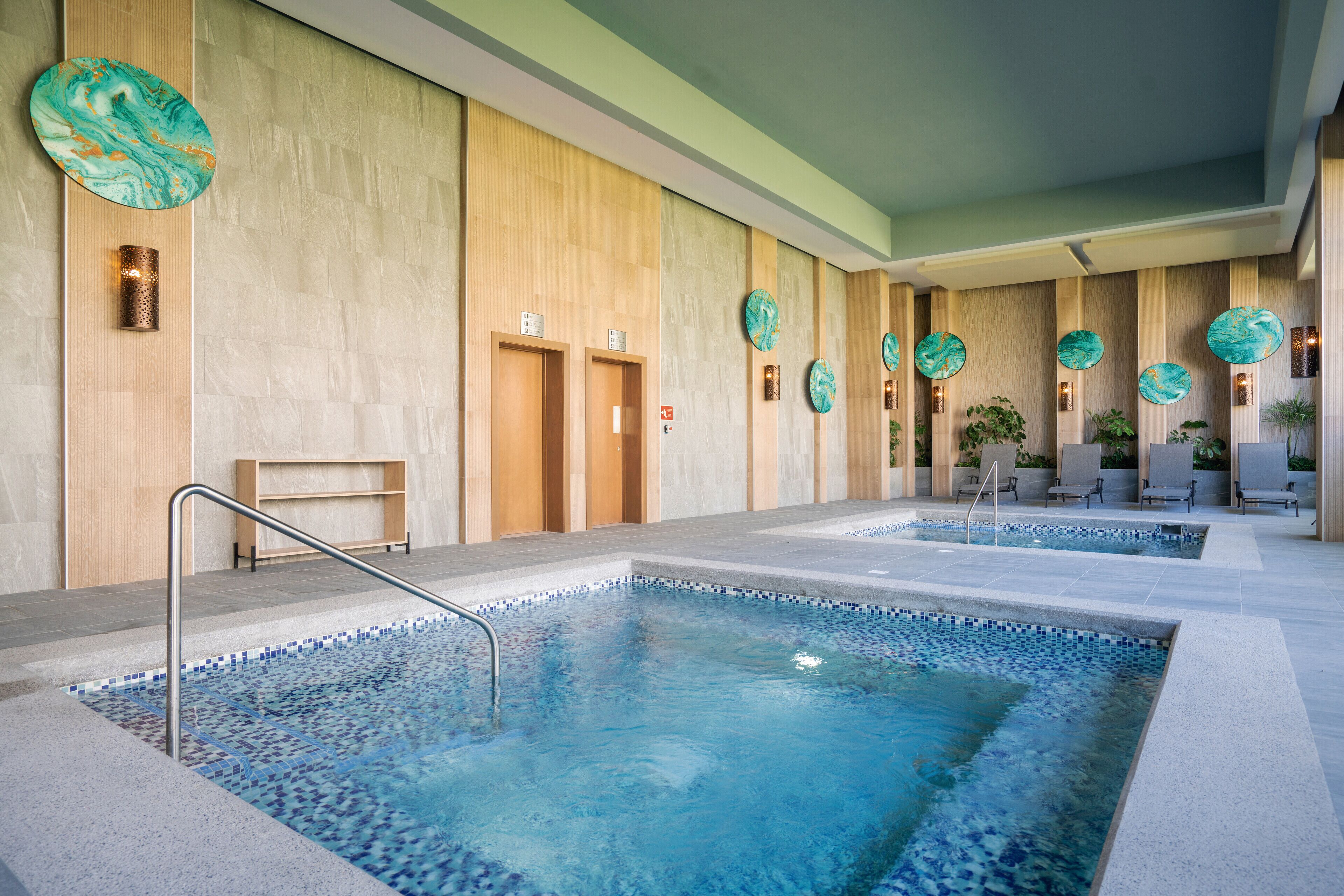 A spa area with two hot tubs, wooden walls, and decorative plates.