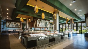 Un moderno vestíbulo de hotel con una zona de buffet central, ventanas amplias e iluminación decorativa.