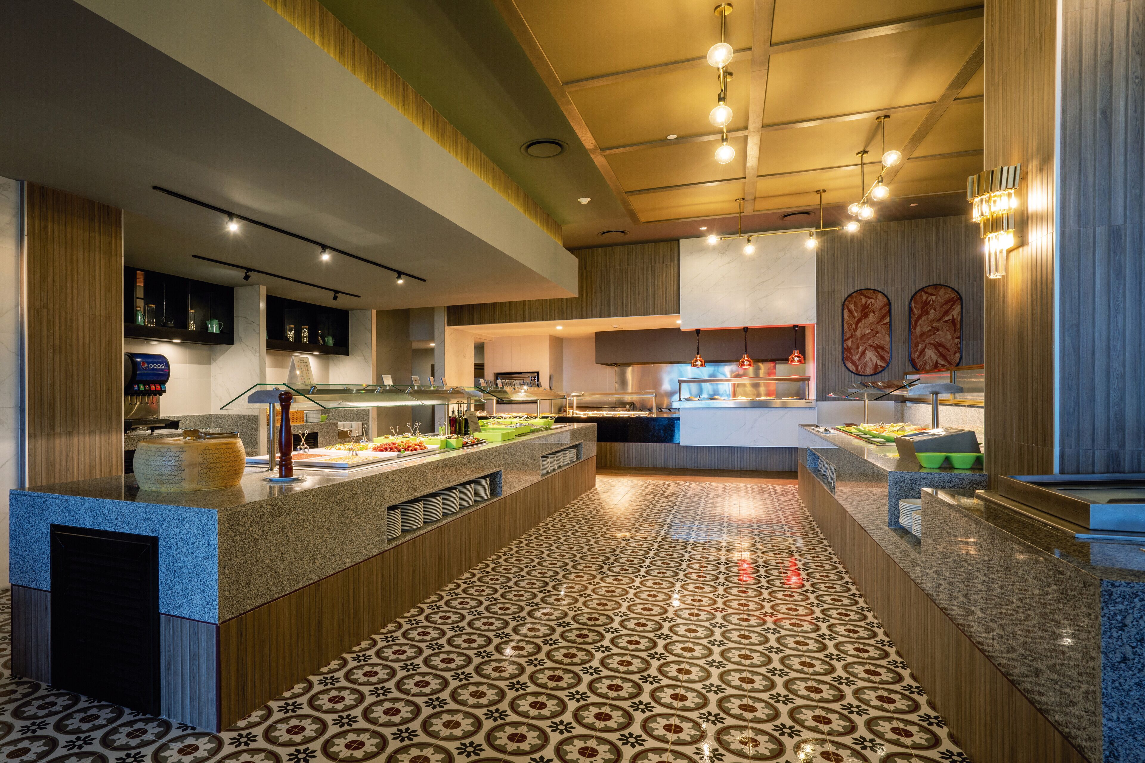 A modern kitchen with granite countertops, a patterned tile floor, and a central island with food displays.
