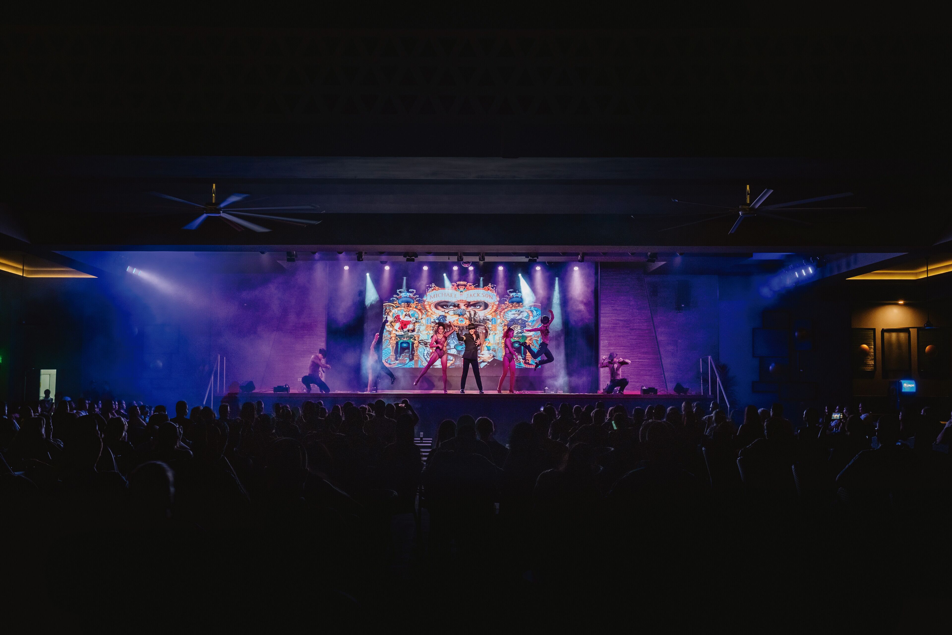 A stage with performers and a large illuminated backdrop.