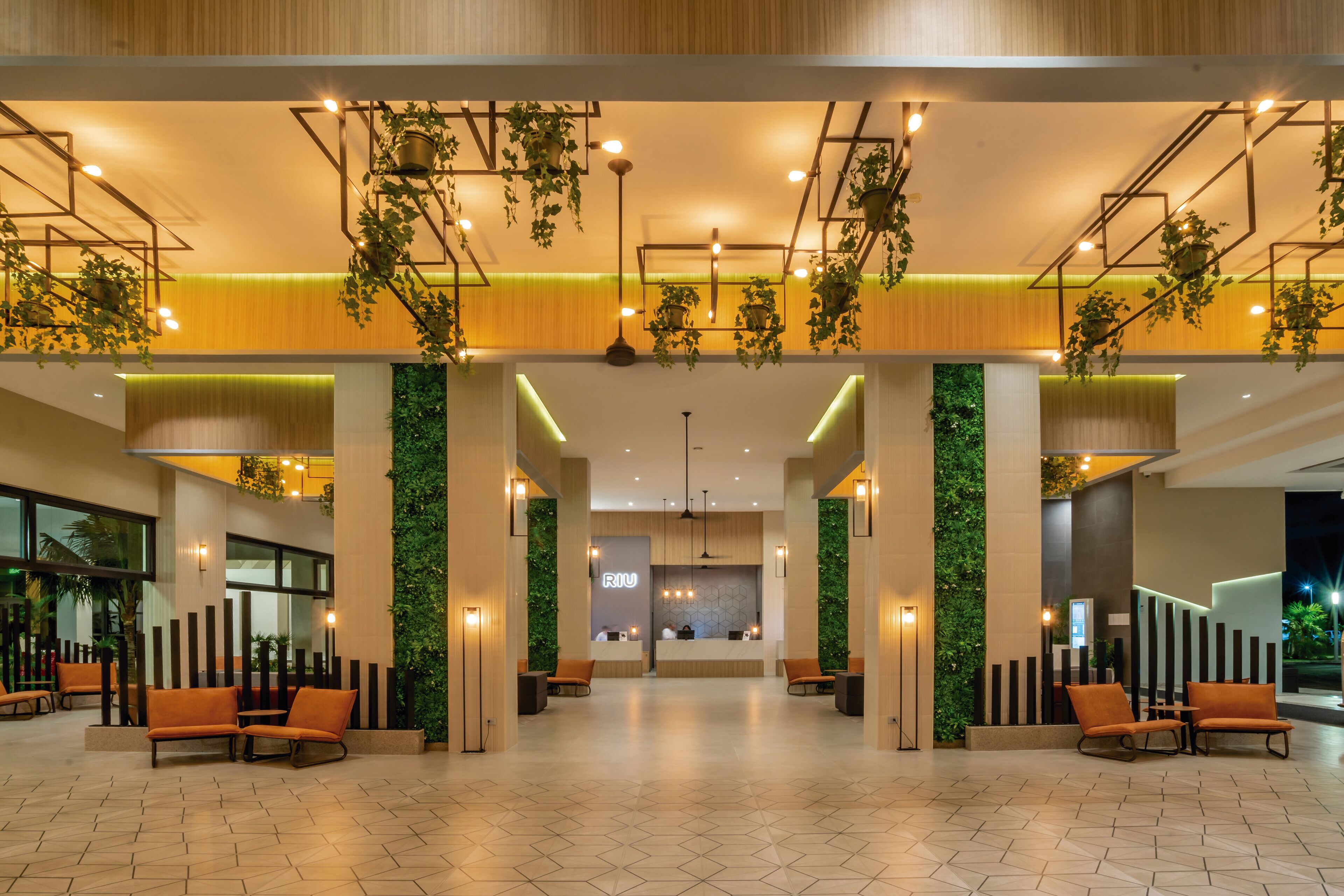A spacious lobby with a reception desk, seating area, and a green wall feature.