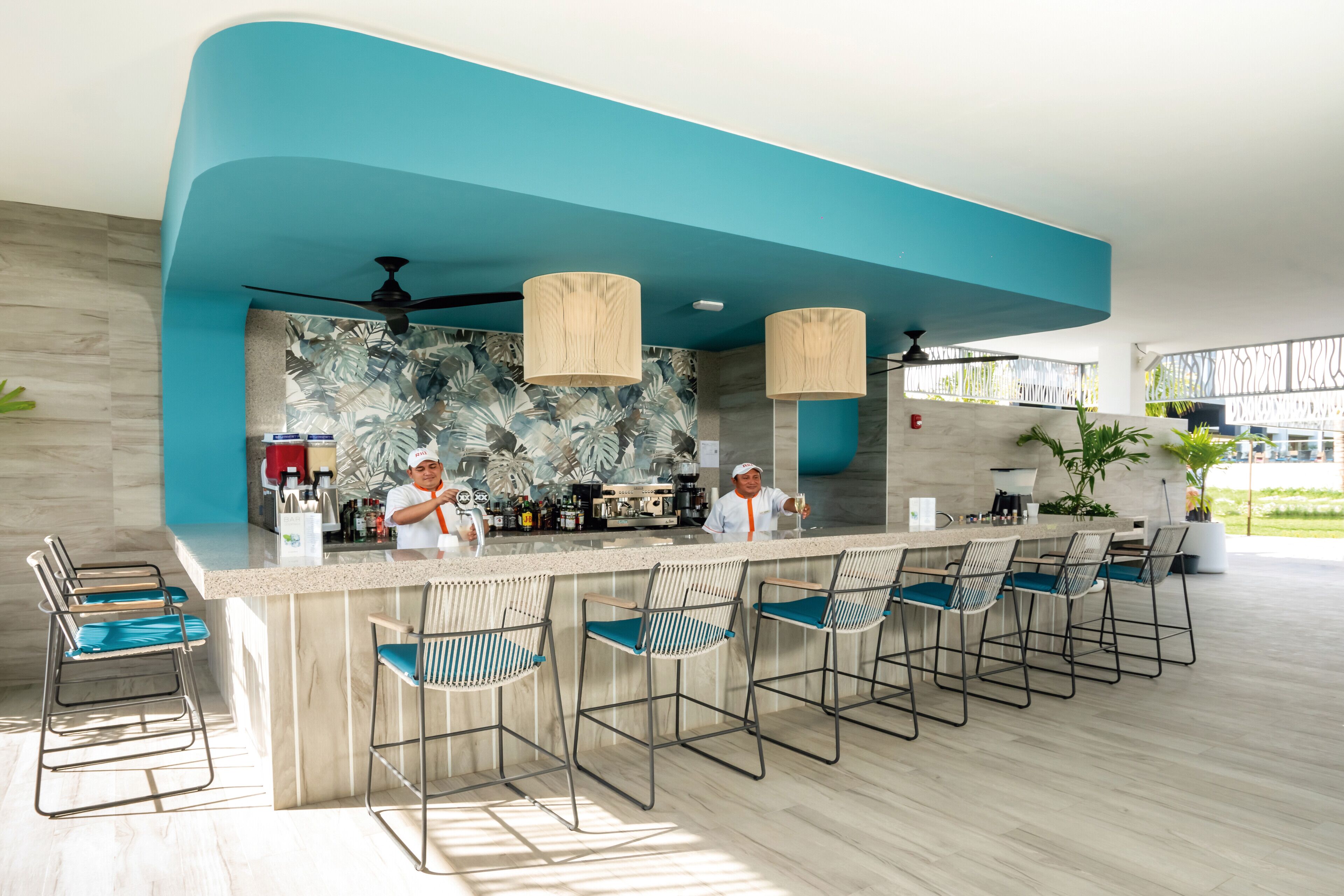 A modern bar area with a teal accent wall, bar stools, and a counter.