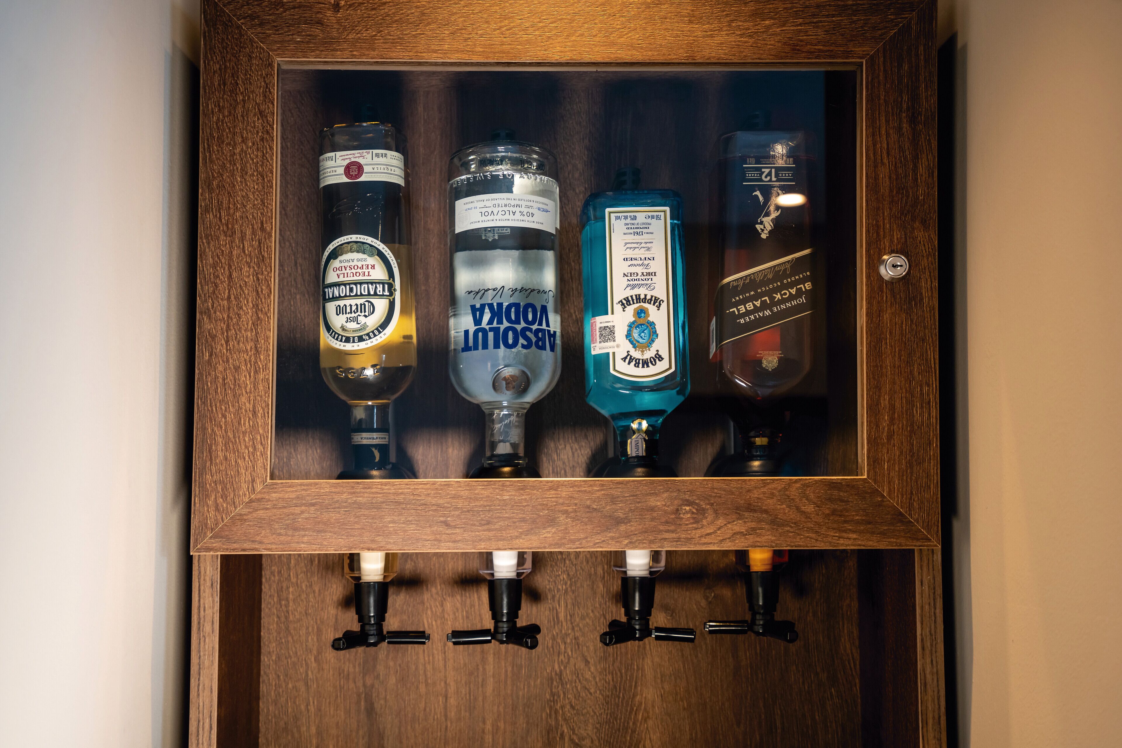 Un armario de madera con cuatro botellas de licor.