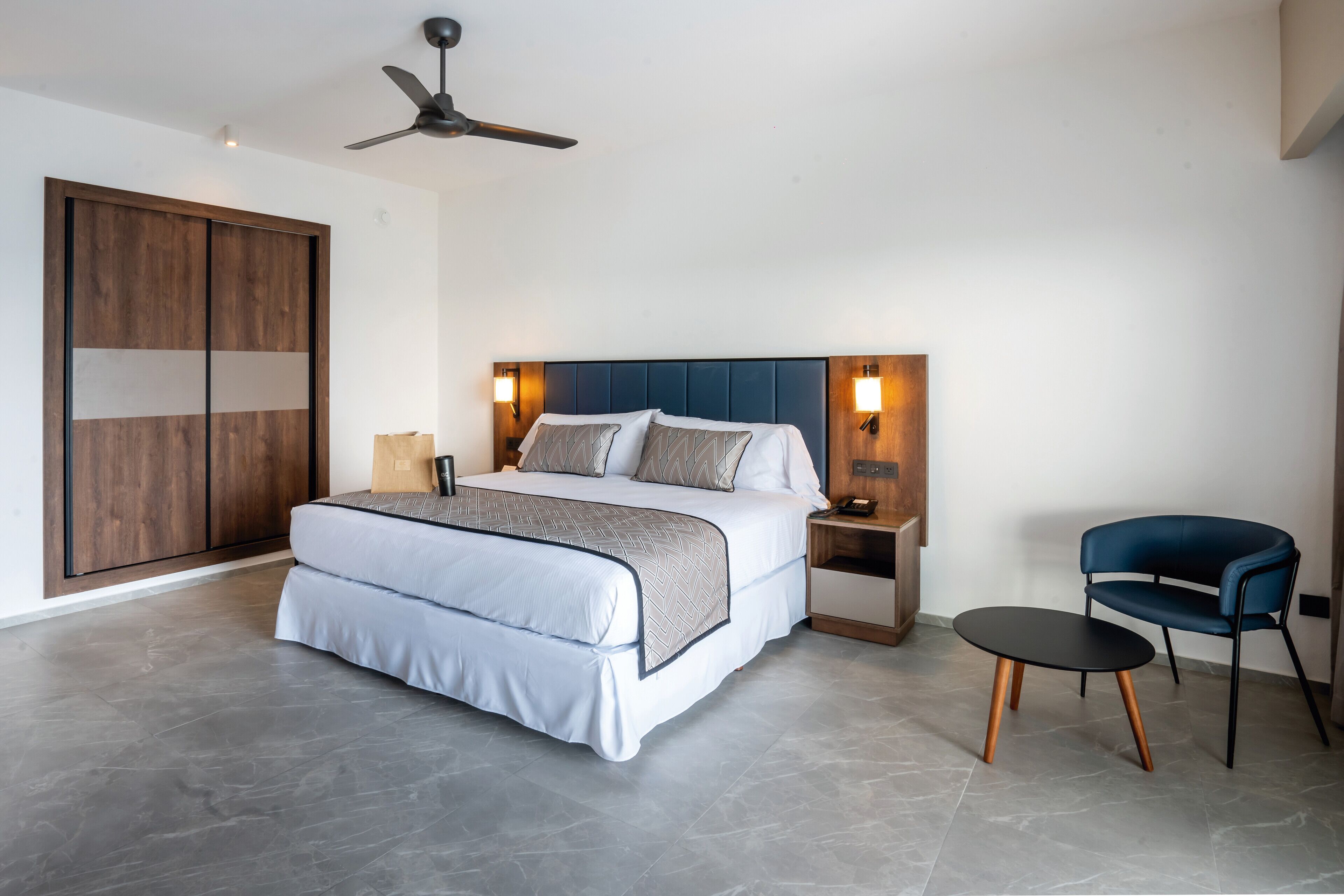 A modern bedroom with a large bed, a desk, and a chair.