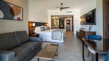 Una habitación de hotel moderna con cama, sofá, mesa de centro, escritorio y televisor.