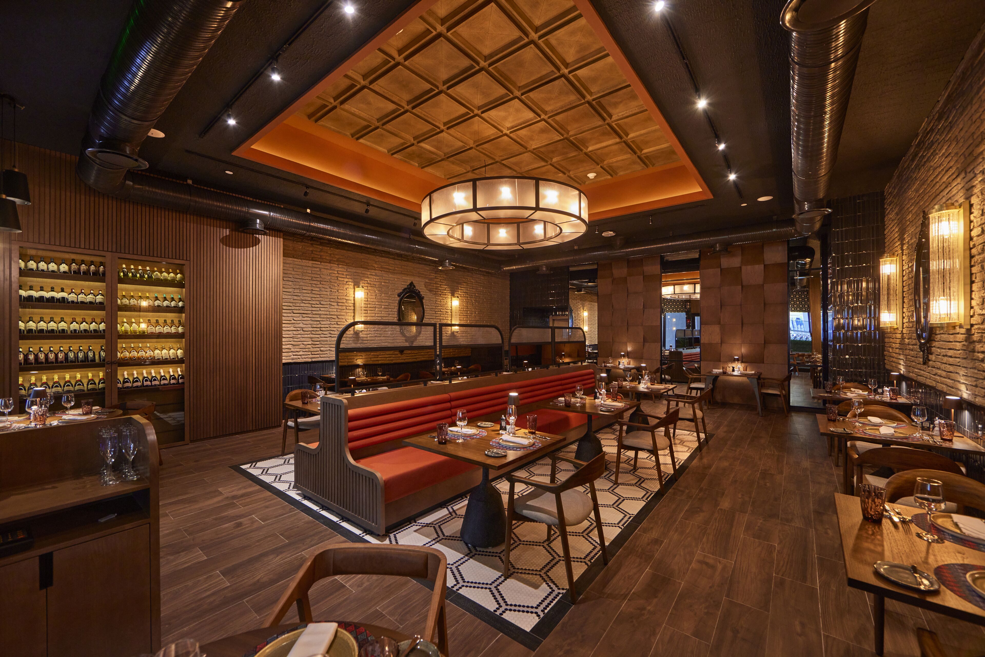 A restaurant with a central seating area, wooden walls, and a brick accent wall.