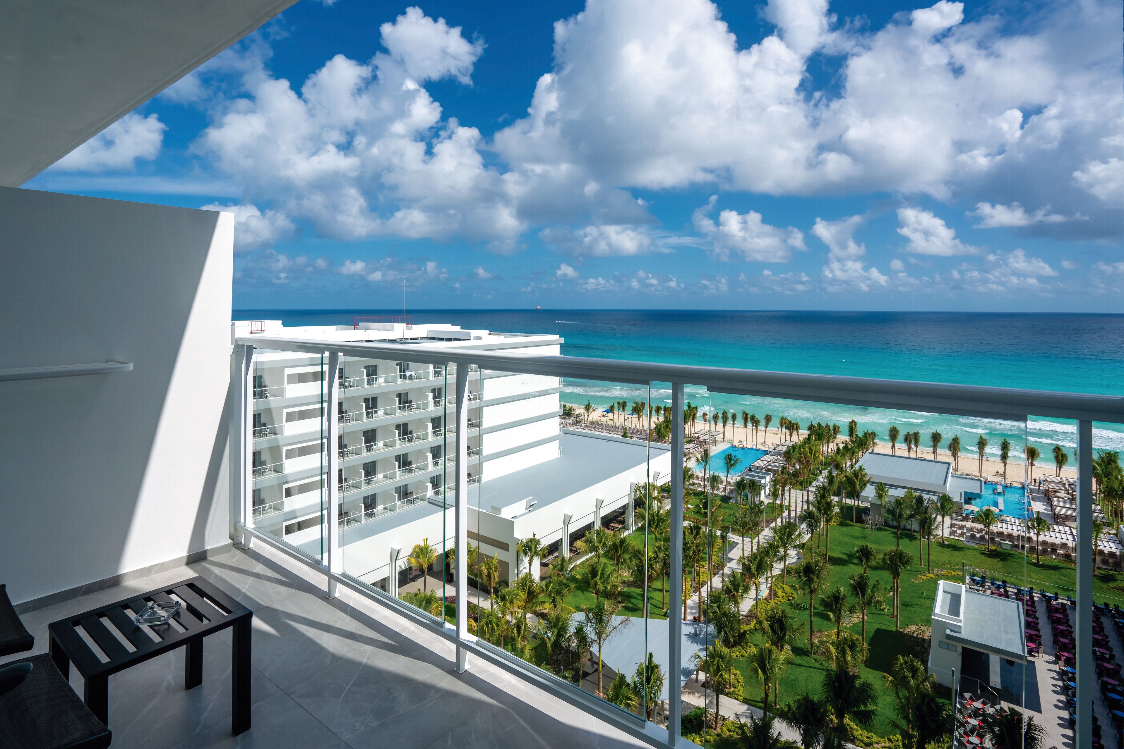 A balcony with a view of a resort, including a pool and beach.