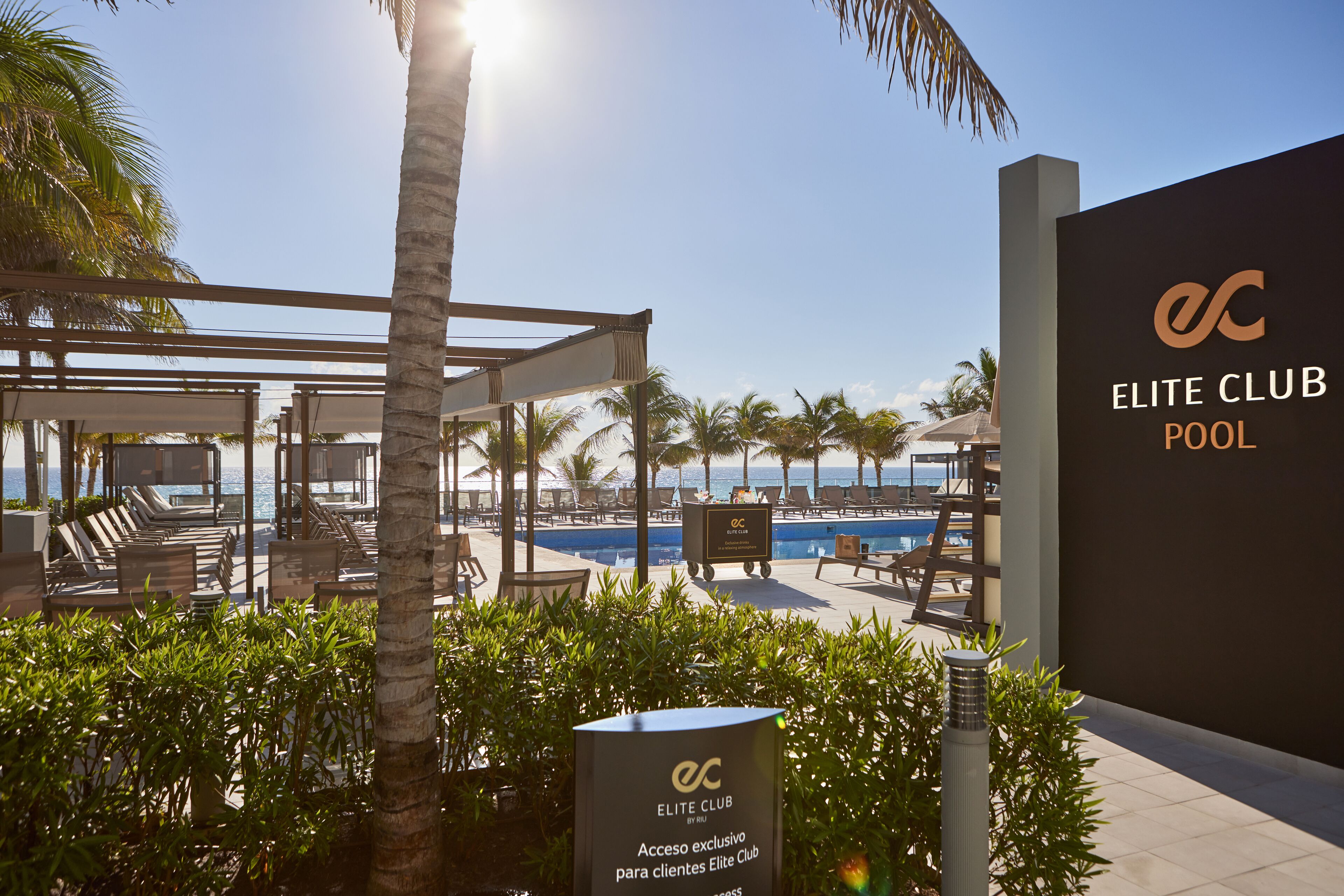 A pool area with lounge chairs and a sign for the Elite Club Pool.