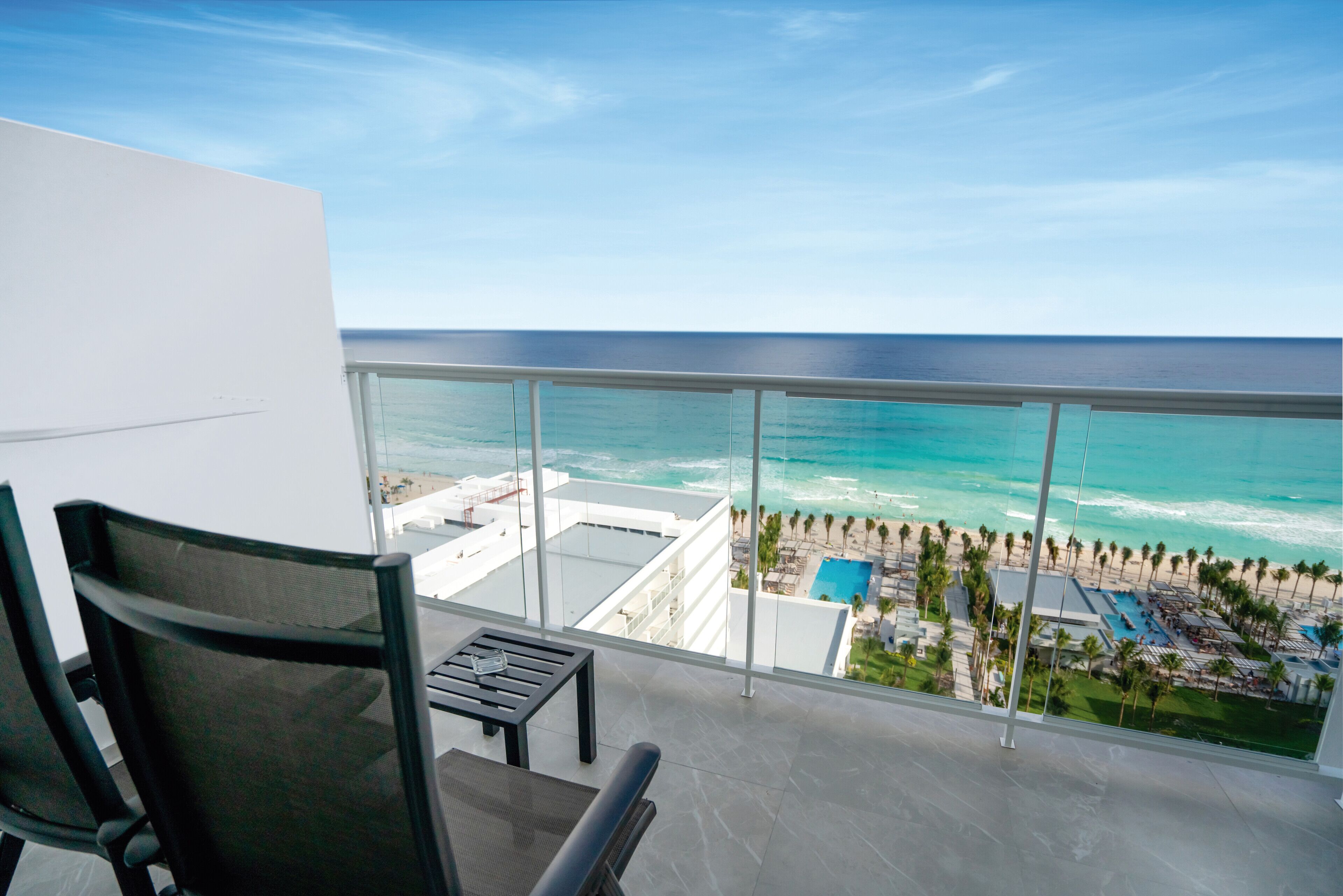 A balcony with a view of the ocean and a resort area.