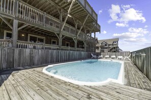Una terraza de madera con un jacuzzi y sillas de descanso.