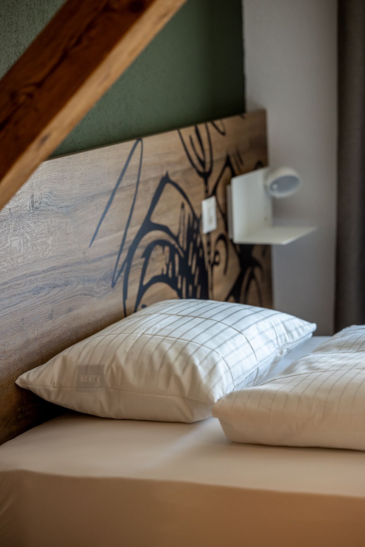 A bed with two pillows, a headboard with a tree design, and a bedside lamp.