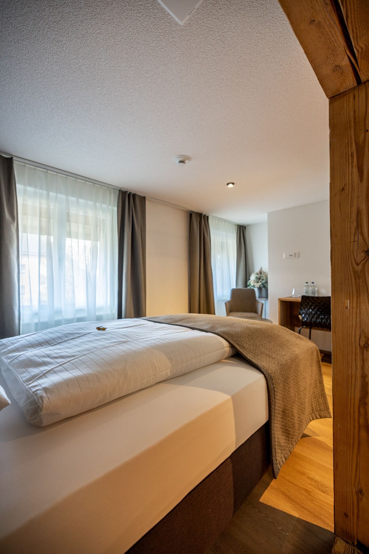 A modern hotel room with a large bed, a desk, and a chair.