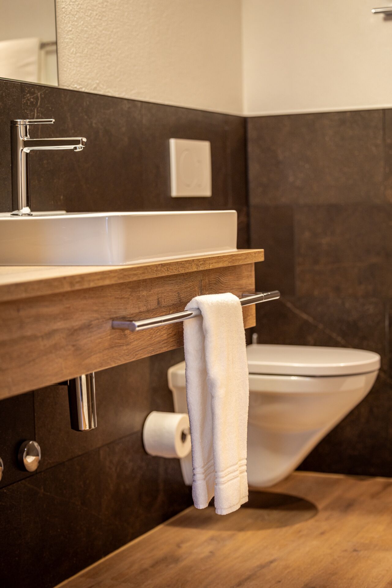 Un baño moderno con tocador de madera, lavamanos blanco y un inodoro.