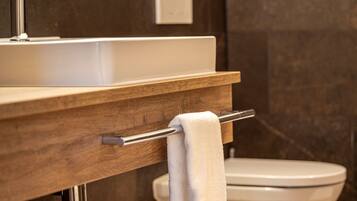 Un baño moderno con tocador de madera, lavamanos blanco y un inodoro.
