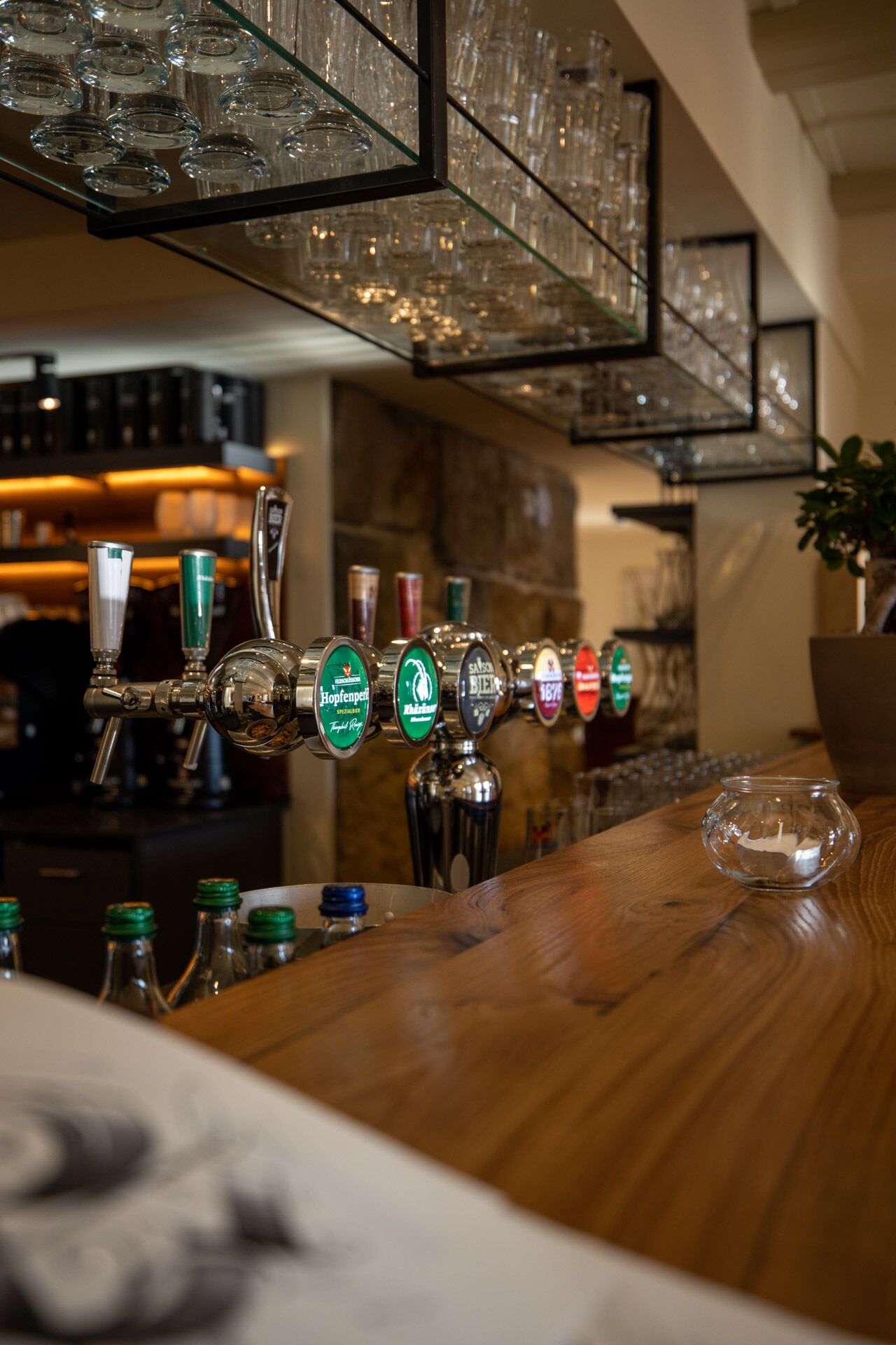 A bar with multiple beer taps, a wooden counter, and a glass display case.