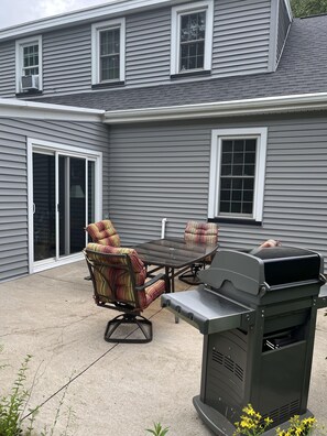 A patio with a grill, outdoor furniture, and a sliding glass door.
