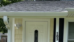 A house with a white front door, a small porch, and a brick foundation.