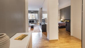 En modern lägenhet med trägolv, en matplats med bord och stolar, ett köksområde och ett vardagsrum med soffa och säng.