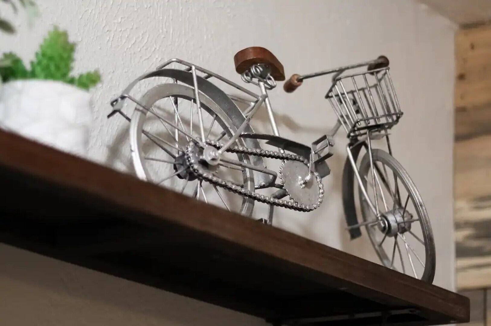 A metal bicycle with a basket on a shelf.