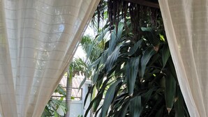 Un espace piscine donnant sur un jardin tropical, entouré de rideaux blancs.