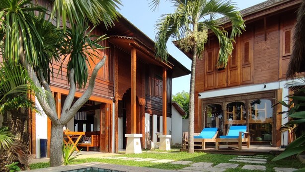 Un espace piscine doté d’un sol carrelé, d’une terrasse en bois et de chaises longues.