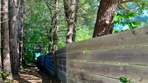 Una cerca de madera con un sendero que atraviesa una zona boscosa.