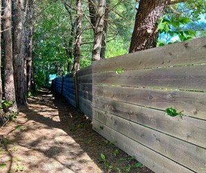 Une clôture en bois avec un sentier qui traverse une zone boisée.