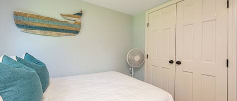 A bedroom with a bed, a wall-mounted fan, and a set of white doors.