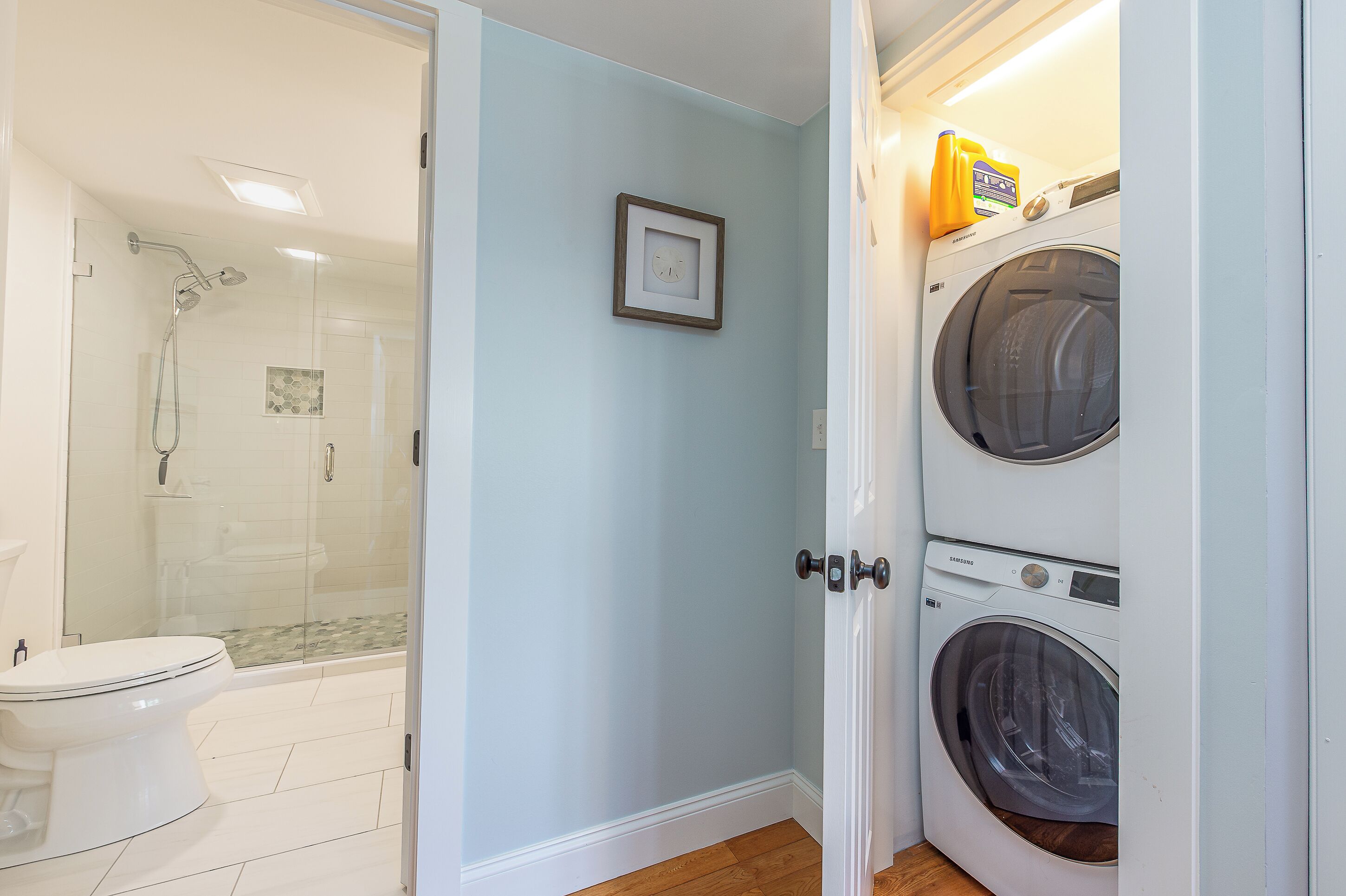 A bathroom with a shower, toilet, and a washing machine.