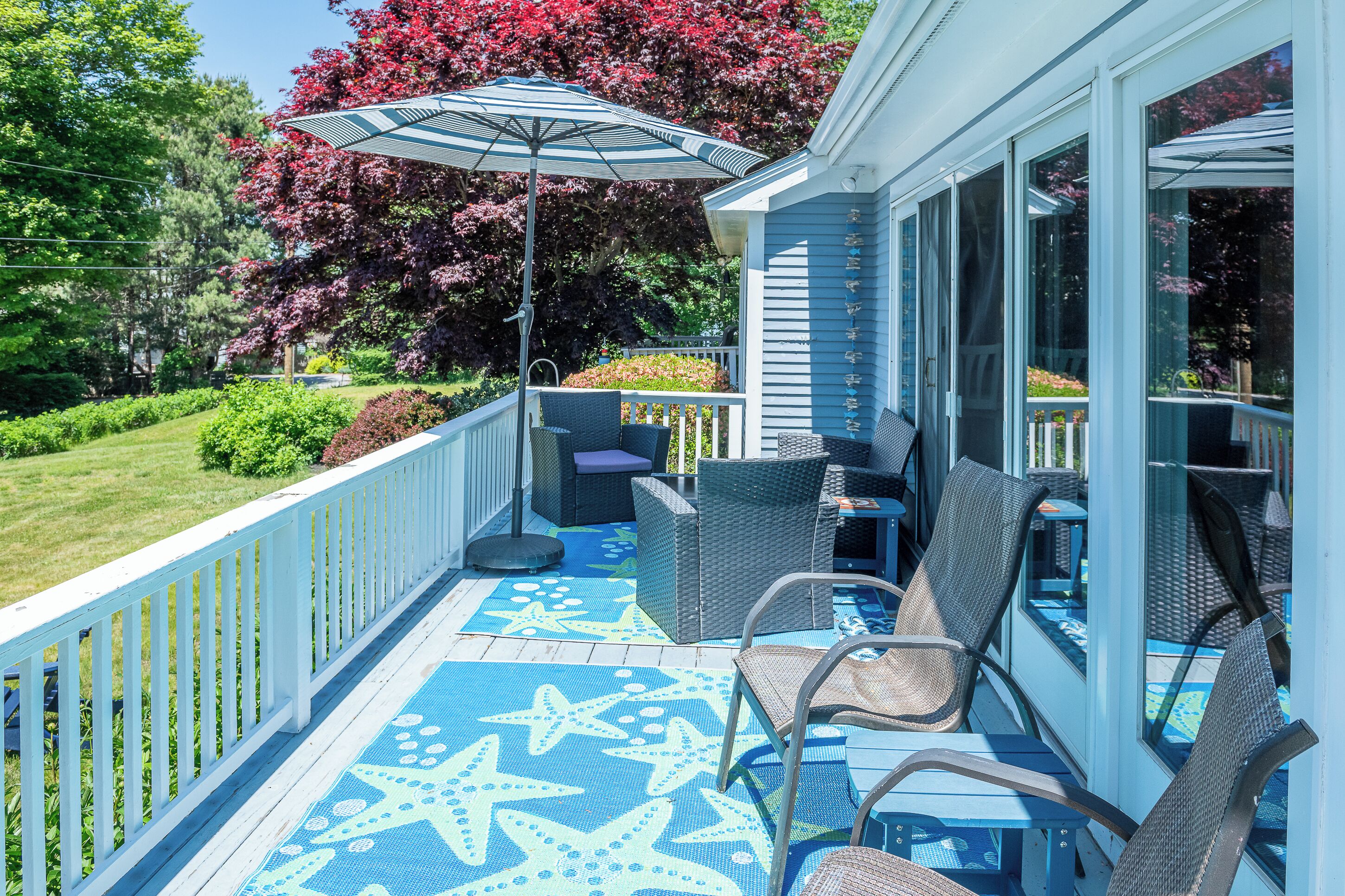 A covered outdoor seating area with wicker furniture, a star-patterned floor, and a large umbrella.