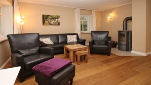 A cozy living room with a sofa set, a coffee table, and a fireplace. - Comfort vacation apartment in Wyk, 4 persons, ground floor in 2-family house, 3 rooms, approx. 84m² (Wyk auf Föhr)