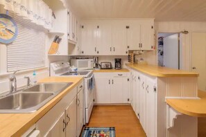 Eine kleine Küche mit weißen Schränken, einer Holz Arbeitsplatte, einer Mikrowelle und einem Toaster.