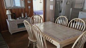 Ein Essbereich mit Holztisch und Stühlen, einem Kühlschrank und einer Küchenarbeitsplatte.