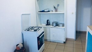 Eine kleine Küchenzeile mit Gaskochfeld, Backofen und einer Ablage für Küchenutensilien.