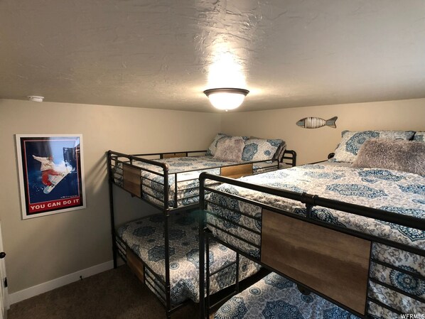 A bunk bed room with a poster on the wall, a ceiling light, and a fish-shaped wall decoration.