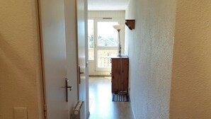 A narrow hallway with a radiator, a door, and a lamp on a wooden cabinet. - 100m from ski slopes, 5th floor, view mountain, balcony, parking, tv, ski locker, 40m², Les 2 Alpes (Les Deux Alpes)