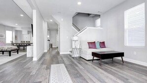 A modern living room with a staircase, a dining area, and a kitchen in the background. - All new beach block Bartram Beach Tower - 8bd home (Atlantic City)