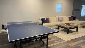 A ping pong table in a living room with a sofa and a coffee table. - All new beach block Bartram Beach Tower - 8bd home (Atlantic City)