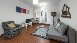 Una sala de estar con sofá, sillón, televisor y elementos decorativos.