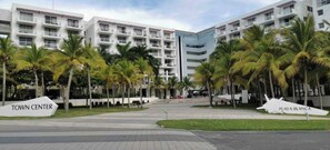 A modern hotel with multiple floors, palm trees, and a sign indicating 'Town Center' and 'Playas Blanca'. - Beach House | Nature | Families, Groups or Home Office | Pet Friendly (Río Hato)