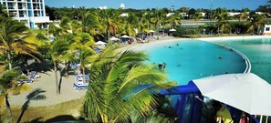 A resort with a large pool surrounded by palm trees and beach chairs.