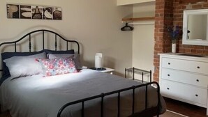 A bedroom with a bed, a dresser, a mirror, and a wall art piece. - Cozy 1-bedroom in Bauer Terrace next to Citadel (Halifax)