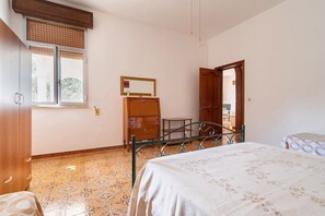 Un dormitorio con cama, armario, espejo y ventana con persianas.